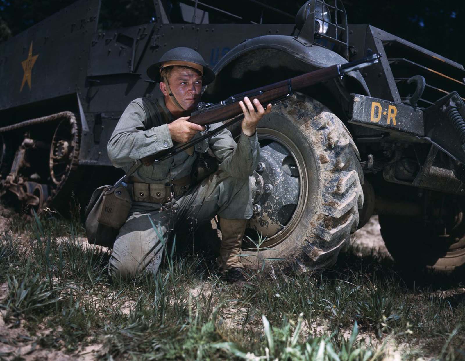 #4 An infantryman crouches beside a half-track with an M1 Garand.