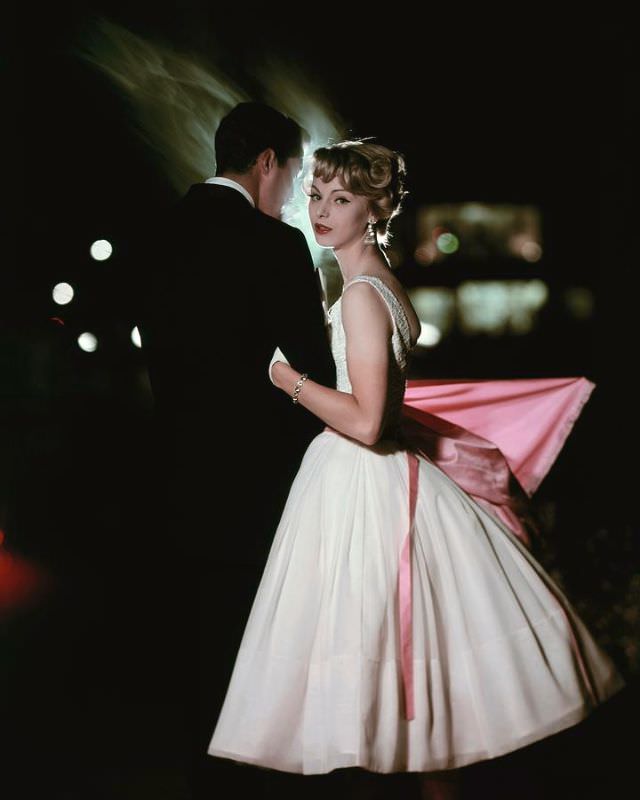 #5 Model is wearing a skirt of white chiffon with bodice of white cotton lace, October 1957