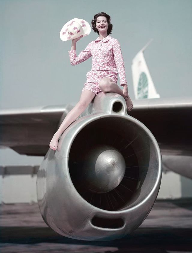 #8 Model sitting atop the engine of Pan Am’s 707 Clipper wearing a pink printed sharkskin jacket, 1959