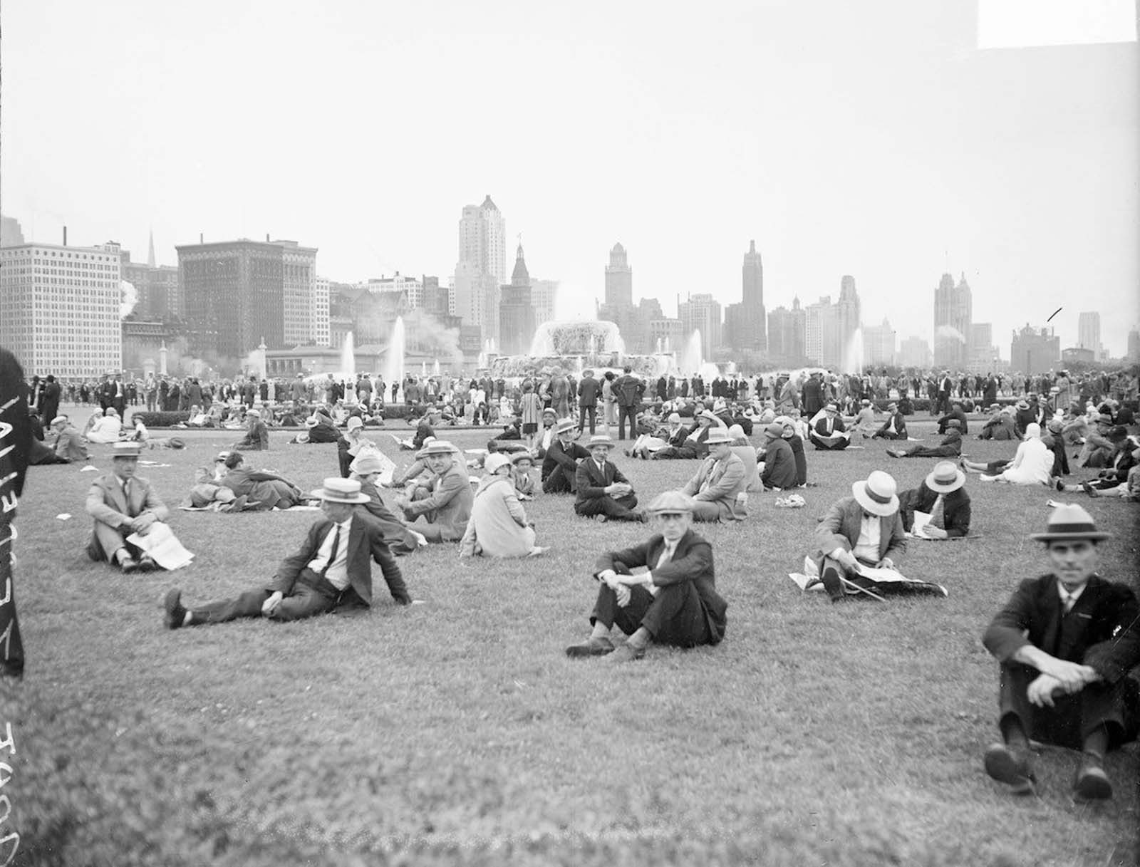 #9 Crowds sitting and standing on a lawn in Chicago’s Grant Park. Buckingham Fountain and buildings are visible in the background.