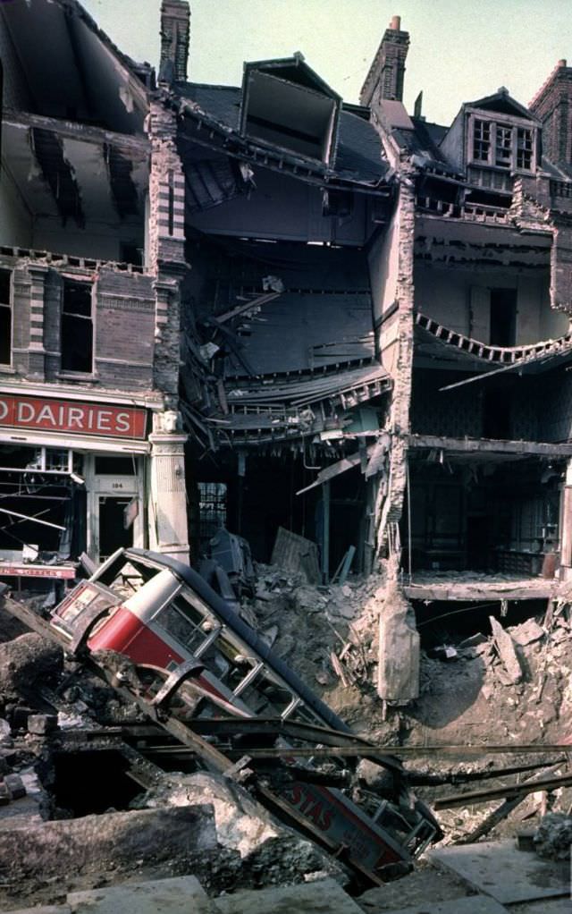 #17 Wreckage of a bus leaning into a huge crater in front of bombed out buildings, a result of German aerial blitz attacks during the Battle of Britain, October 15, 1940