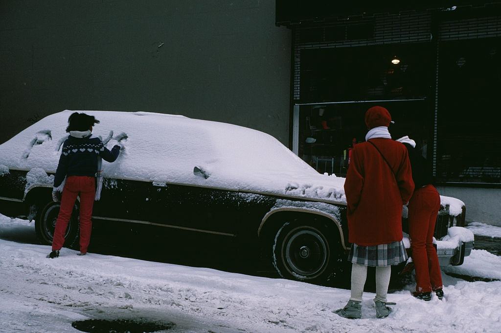 #115 A girl writing in the snow covering a car in New York City, during the blizzard of January 1996.
