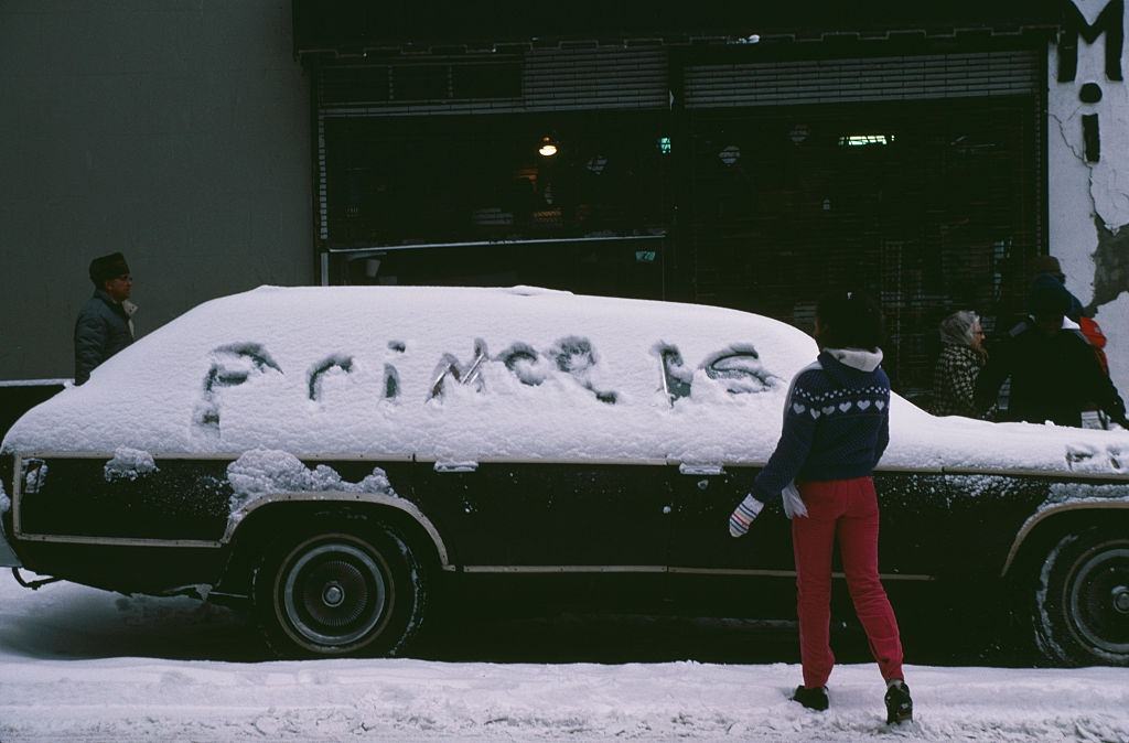 #32 A girl writing in the snow covering a car in New York City, during the blizzard of January 1996.