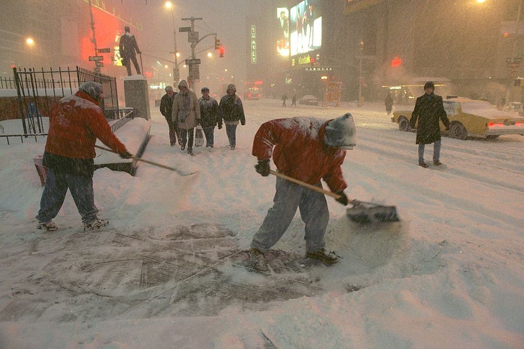 #46 Workers shovel snow from the sidewalk in Times Square during, New York City, 1996