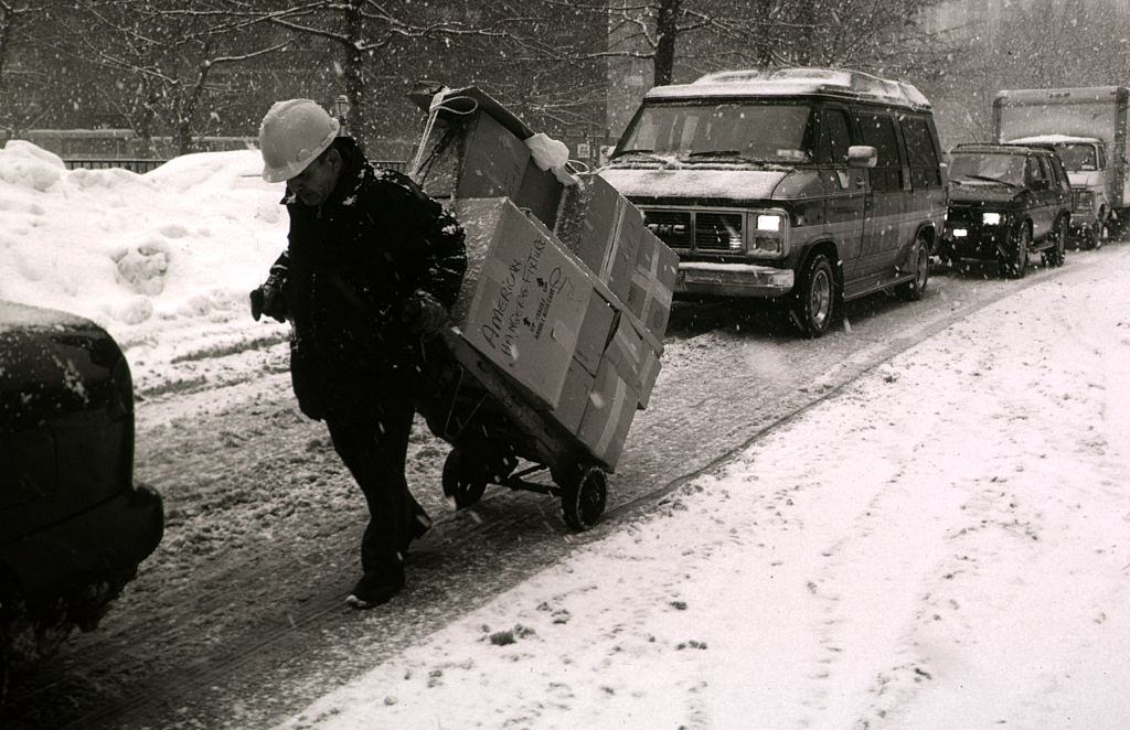#54 A delivery of goods is pulled by hand in the middle of snow bound traffic during one of the worst blizzards in New York City’s history.