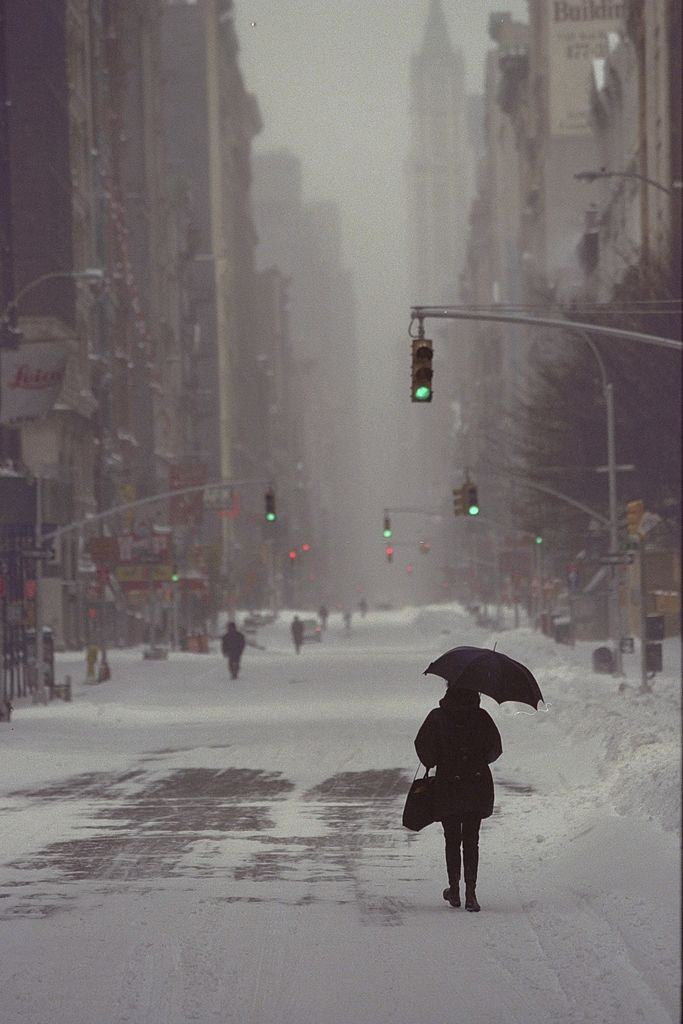 #64 Pedestrian walks down the middle of the street as she makes her way downtown. Sidewalks were piled up with snow after a blizzard.
