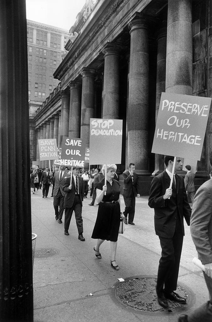 #106 Protesters marching with placards outside Penn Station to save the building from demolition, New York City. Their signs read ‘Preserve Our Heritage’ and ‘Stop Demolition.
