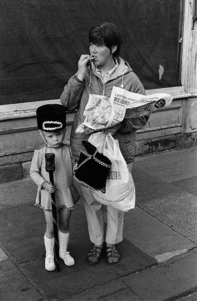 #63 A little girl in a drum majorette costume with her mother, who is carrying another Majorette’s military style hat, in Newcastle Upon Tyne, 1973.