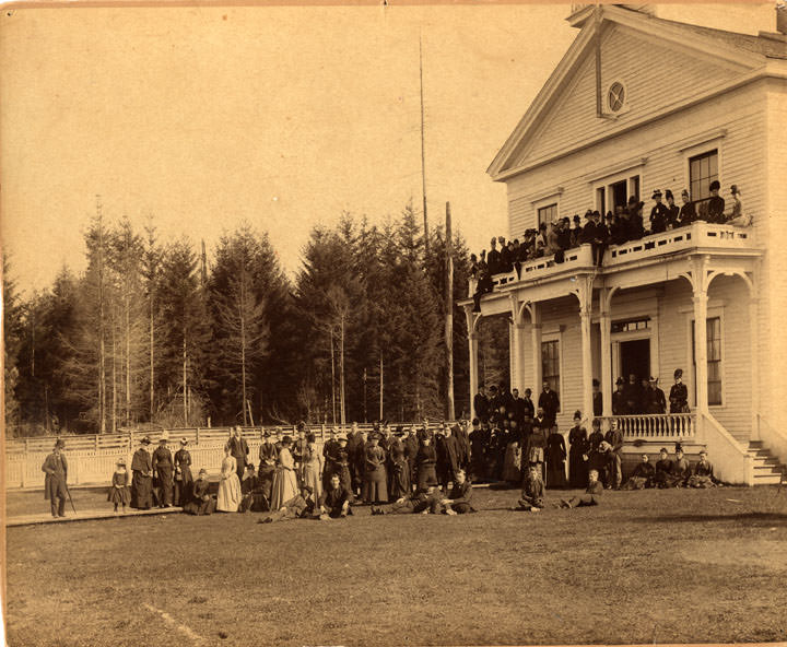 #38 A large group of men and women, and at least one child, in front of and on the balcony and porch of Olympia, 1889.