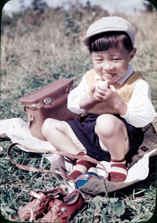 #118 Young boy in a knit vest and a cap eating