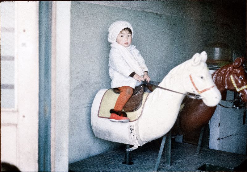 #122 Young girl in a hat riding a toy horse