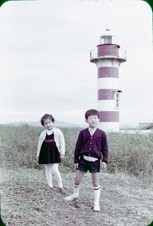 #125 A boy and a girl standing in front of a lighthouse
