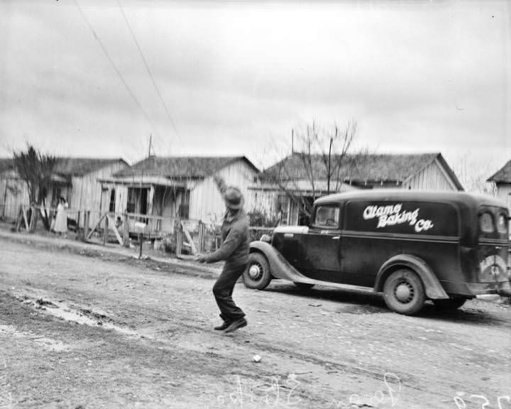#3 A striking pecan sheller throws a stone as he stands in the street, 1938
