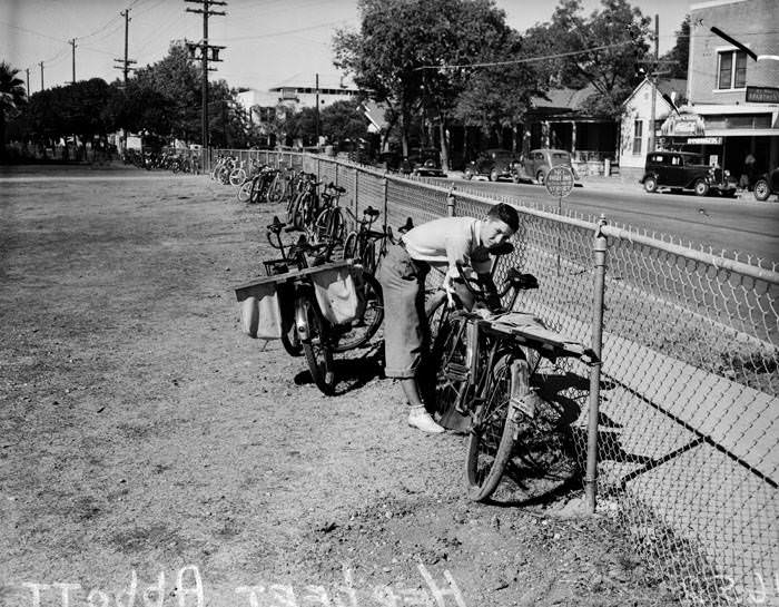 #92 Herbert Abbott chaining bicycle to fence, 1937