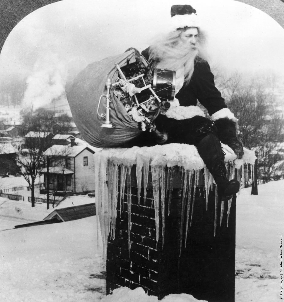#22 Santa Claus brings a sack full of toys down a chimney on a snowy rooftop, 1925