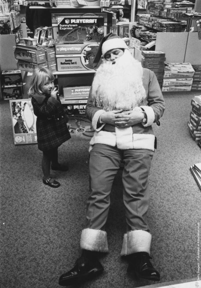 #24 A young girl finds Father Christmas asleep at Bourne And Hollingsworth store in Oxford street, London, 21st December 1976