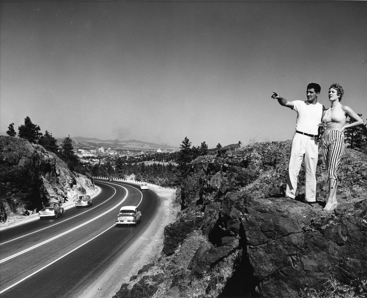 #34 A man and woman standing on a rock formation above a highway, 1940s.
