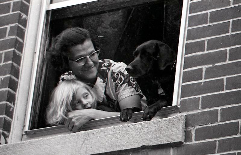 #26 Woman, child, and dog watching North End Christmas Parade from a window