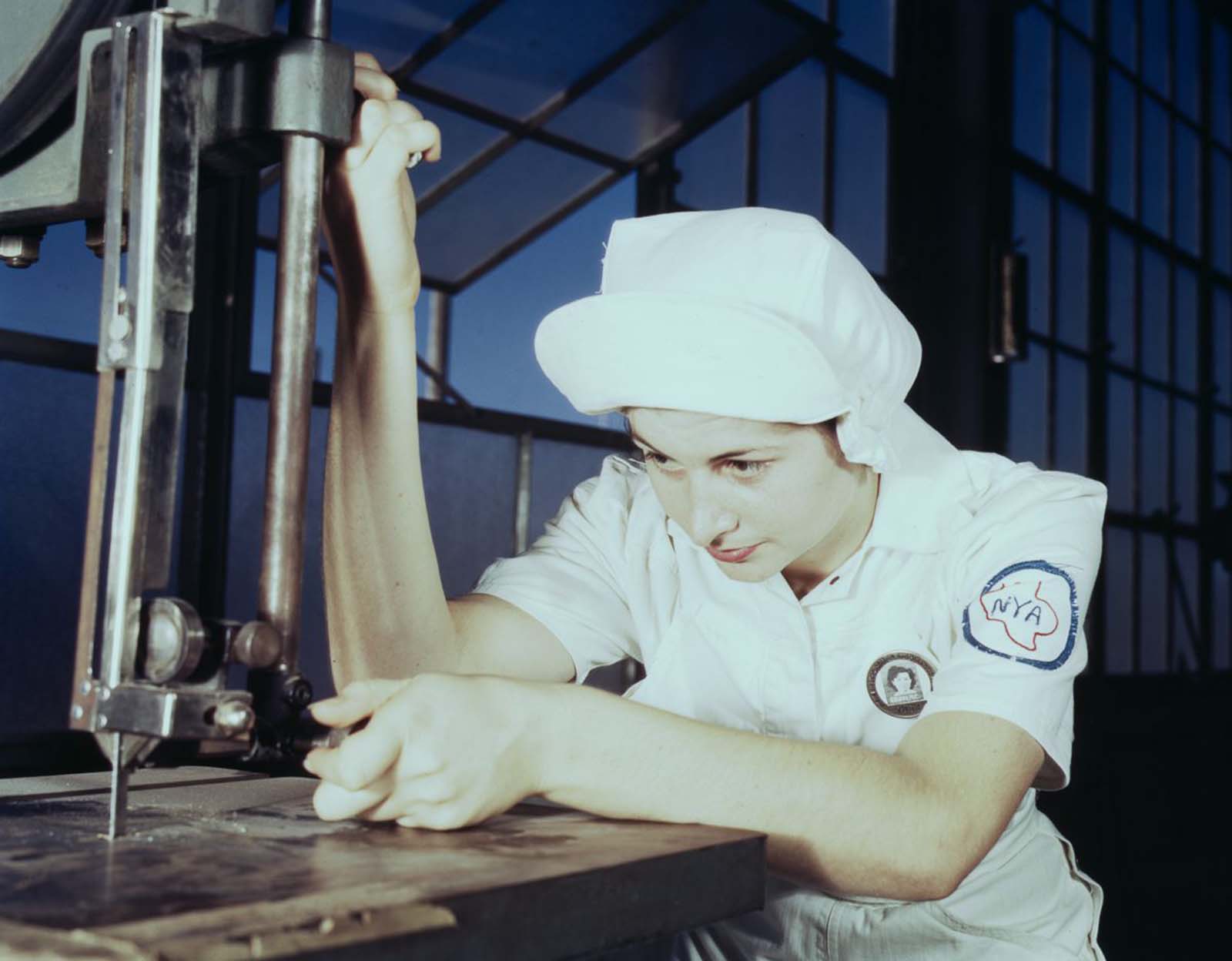 #10 Mildred Webb, an NYA trainee at the base, learns to operate a cutting machine in the Assembly and Repair Department.