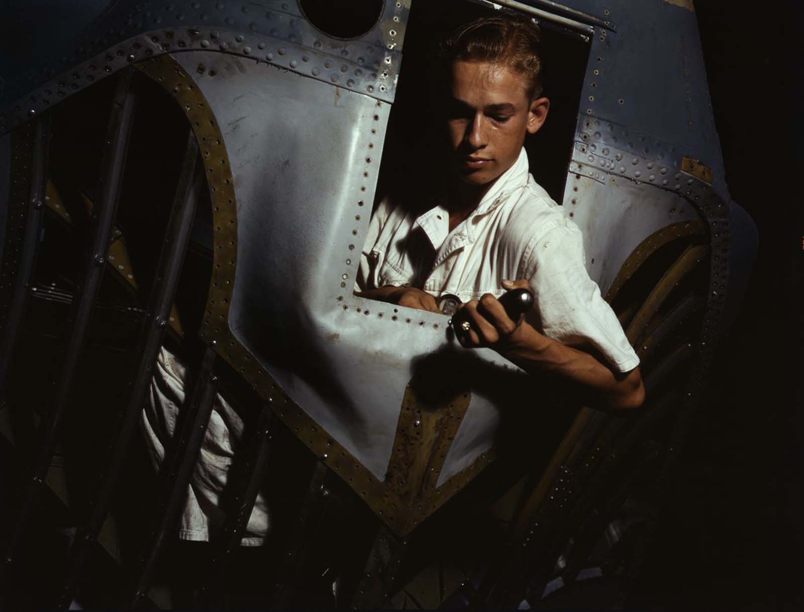 #6 Working inside the nose of a PBY, Elmer J. Pace learns the construction of Navy planes.