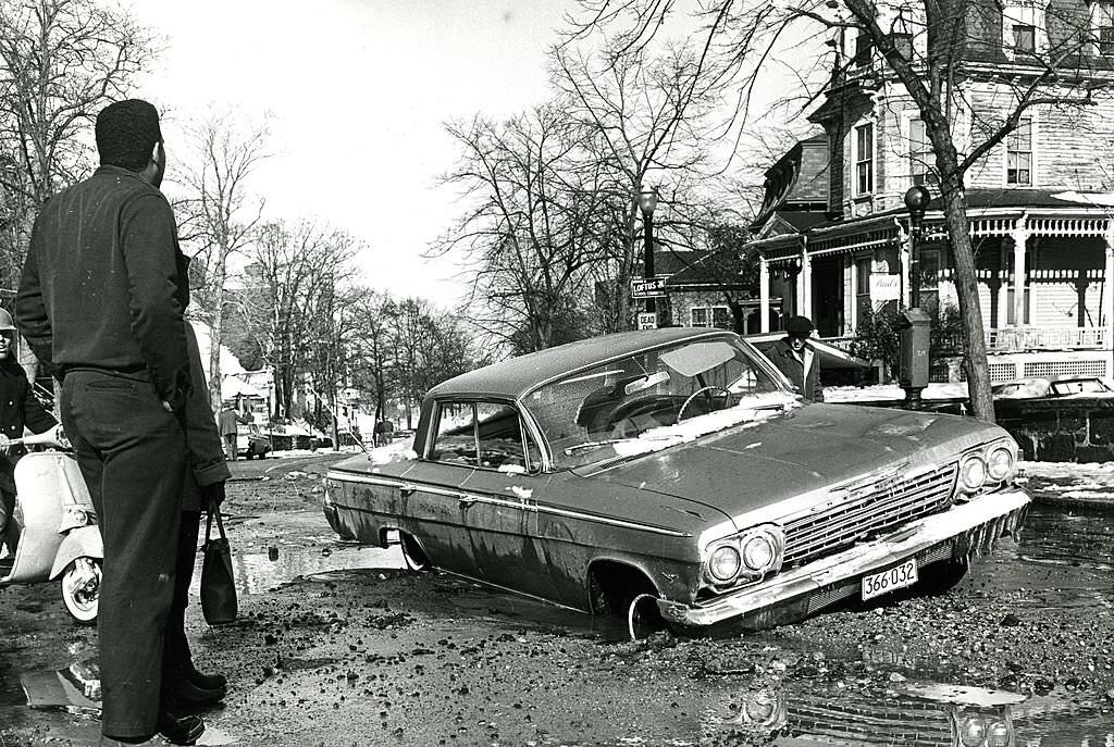#201 This car was half-buried about a foot deep in this pothole in front of 516 Warren St. in Boston.
