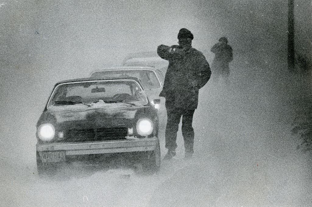 #49 People walk by cars trying to make it through the heavy snow and low visibility on Feb. 6, 1978.