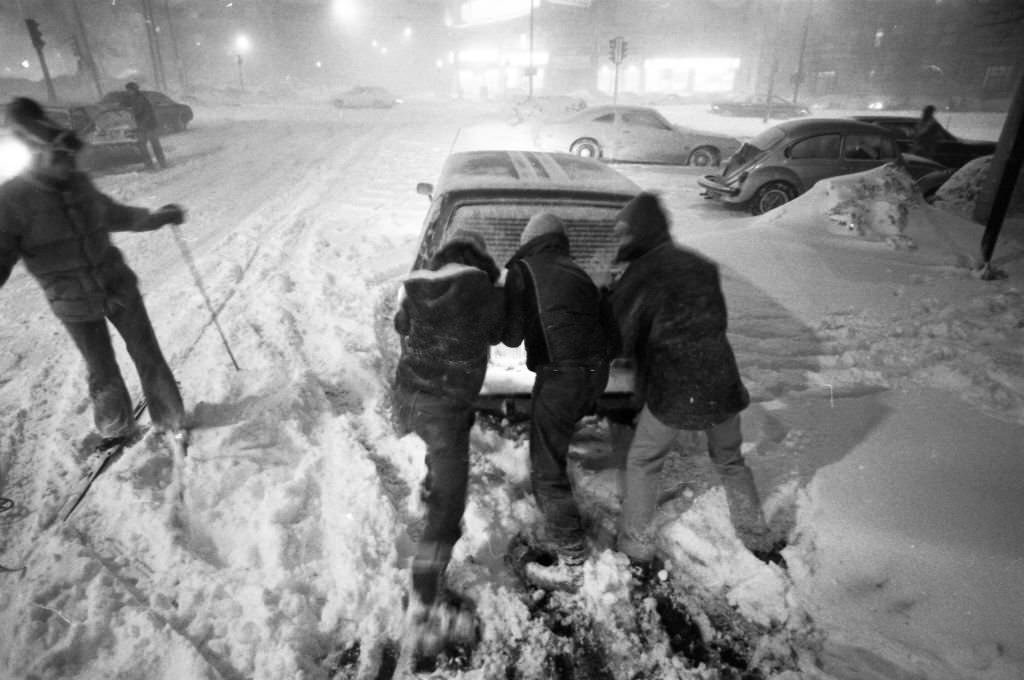 #51 Three people push a disabled car as a skier passes on Kelton Street near Commonwealth Avenue in Boston on Feb. 6, 1978.