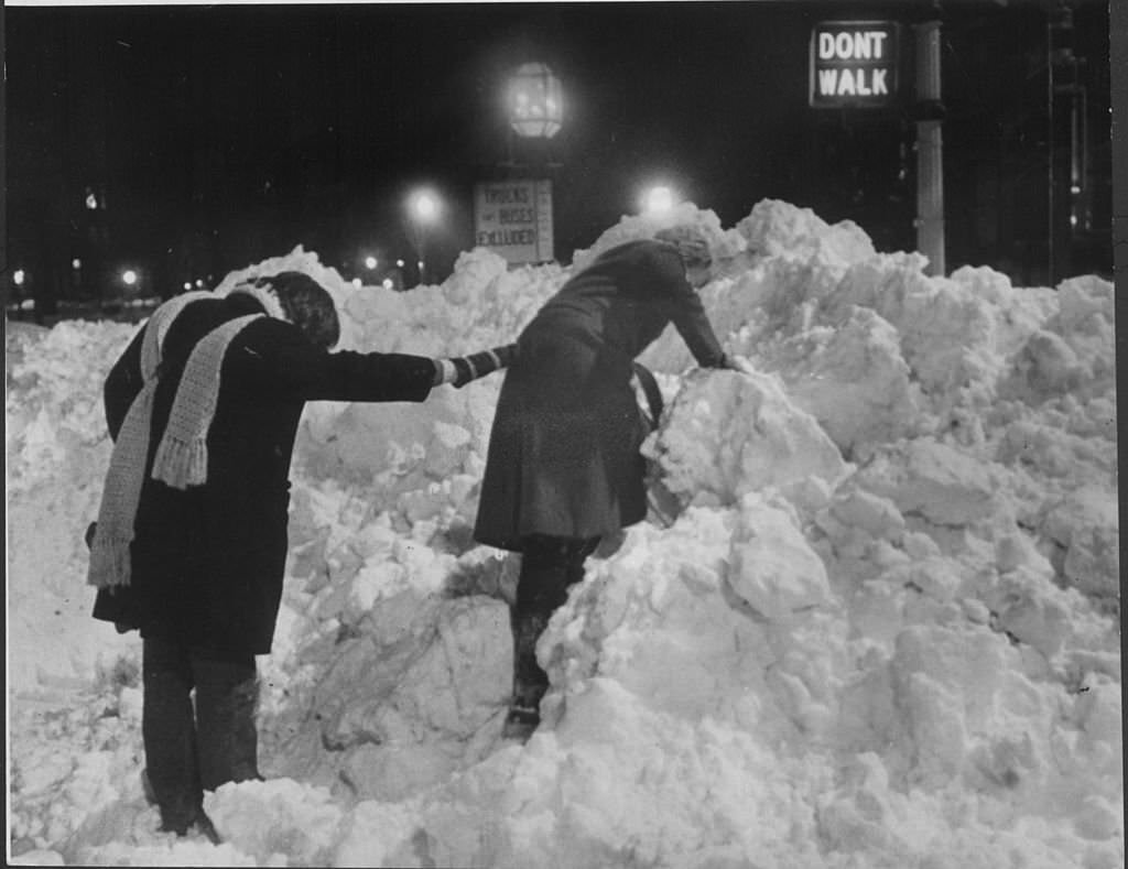 #71 Pedestrians climb through tall piles of snow left behind by the “Blizzard of 78”, while crossing the street near Commonwealth Avenue in Back Bay on Feb. 10, 1978.