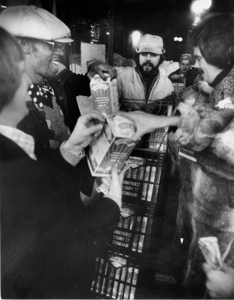 #77 Pete Cole is surrounded by customers looking to buy the milk he is delivering to a store in Boston at midnight on Feb. 10, 1978.