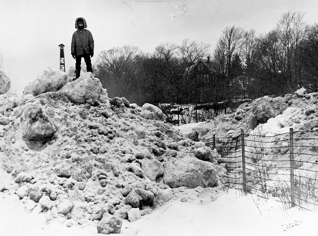 #132 Stephen Bagley, 8, is king of the mountain of snow blocking Grew Avenue in Boston’s Roslindale area, 1975.