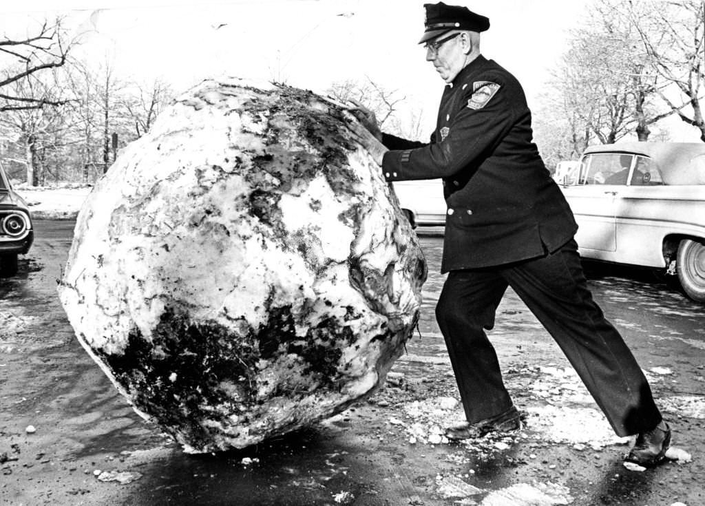 #42 Boston police officer George Floyd pushes a giant snowball out of the way of blocked traffic in the Fenway neighborhood of Boston on Jan. 14, 1966.
