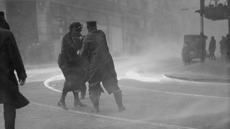 #6 Police officer helps woman through blinding snow during a blizzard in Boston, 1920