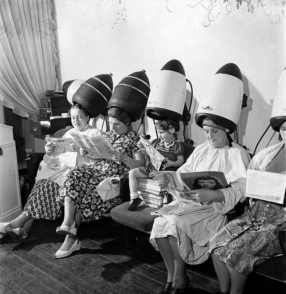 #60 Old women sitting with their heads under a dryer as they get their hair styled, 1953s