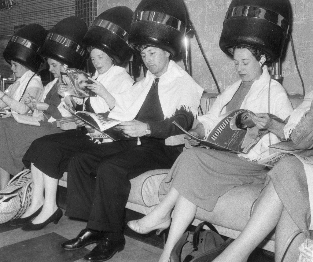 #64 A man surrounded by women under the hairdryers at a new unisex hairdresser’s, 1950s