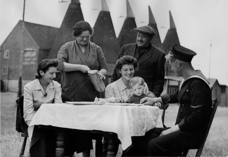 #19 A host serves lunch to a hop picking family in Kent, 1944.
