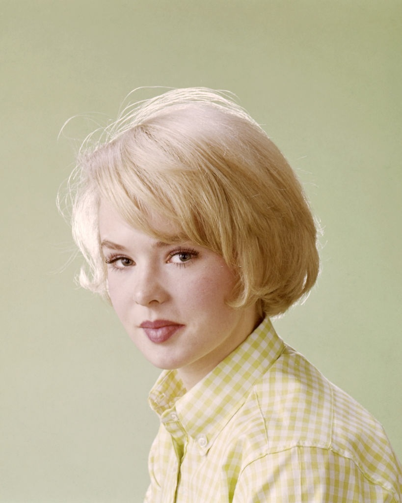 #13 Joey Heatherton, wearing a yellow and white check blouse in a studio portrait, against a yellow background, circa 1965.