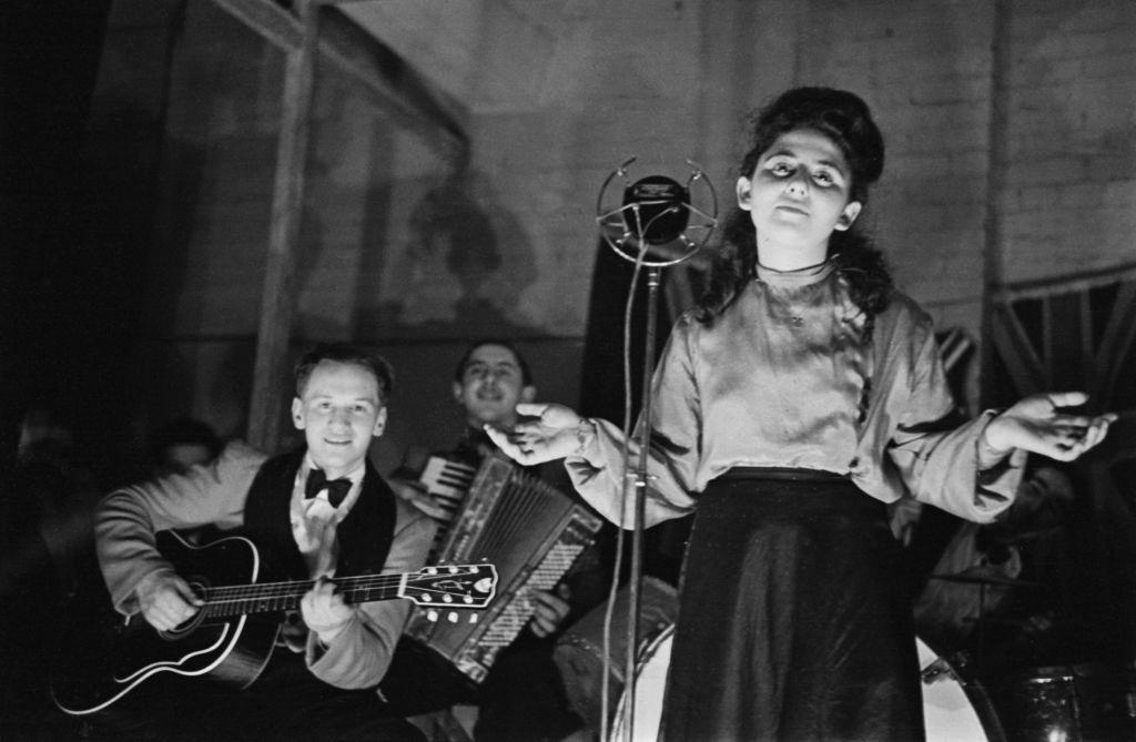 #14 Shop worker Sadie Davis entertains her fellow employees with a song at the Dickens & Jones bomb shelter in the basement of the department store in Regent Street, London during the Blitz in World War II in March 1941.