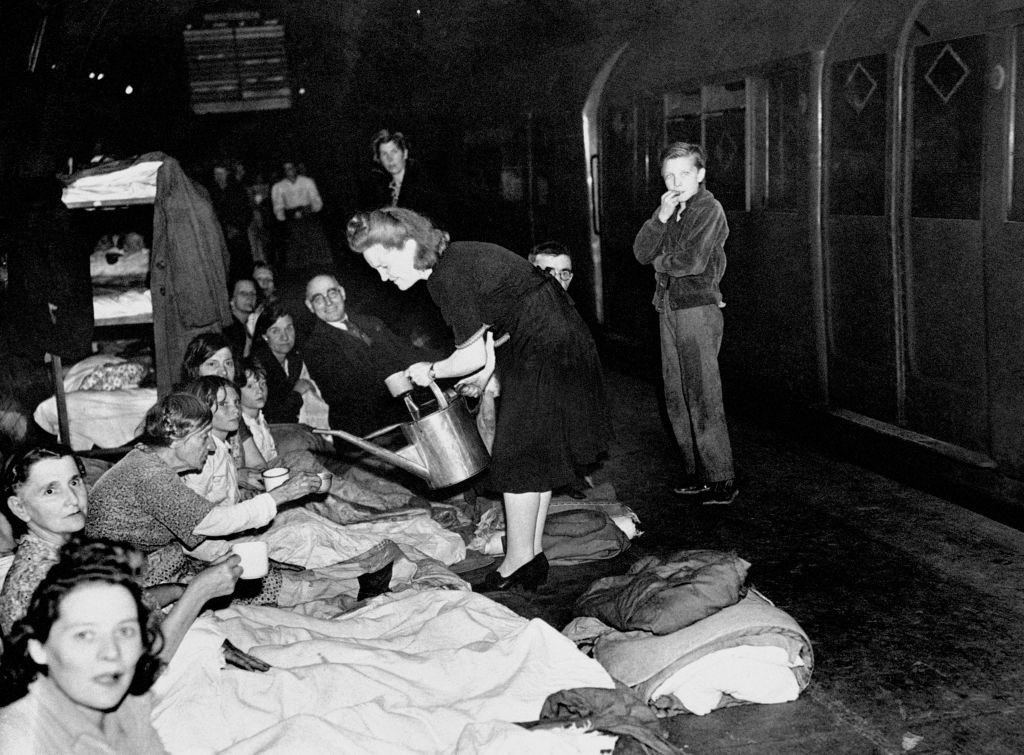 #11 A woman dispenses water from a watering can as Londoners take shelter in the London Underground during the Blitz.