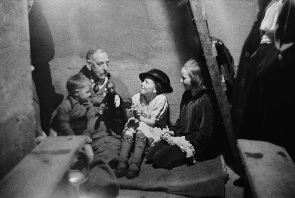 #36 A man entertaining three children with a toy in an air raid shelter during the Blitz, London, October 1940.