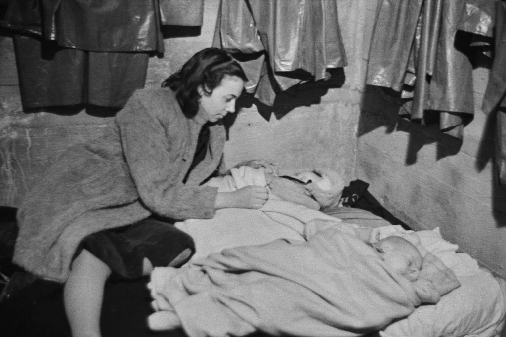 #41 A woman tending to two babies in an air raid shelter during the Blitz, London, October 1940.