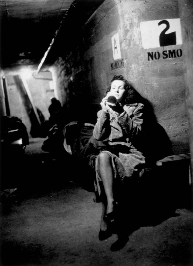 #49 A woman applies make-up while waiting in a shelter during the Blitz, London, October 1940.