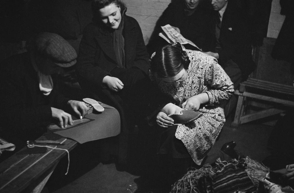 #17 Londoners making slippers in a craft lesson given by London County Council (LCC) teachers at an air raid shelter in Bermondsey, London during the Blitz, March 1941.