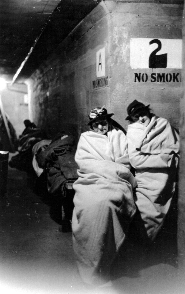 #51 Two women wrapped up in blankets in an air raid shelter during the Blitz, London, October 1940.