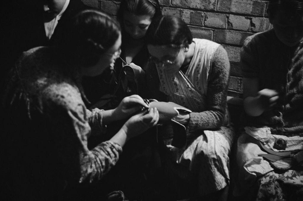 #18 Londoners making slippers in a craft lesson given by London County Council (LCC) teachers at an air raid shelter in Bermondsey, London during the Blitz, March 1941.