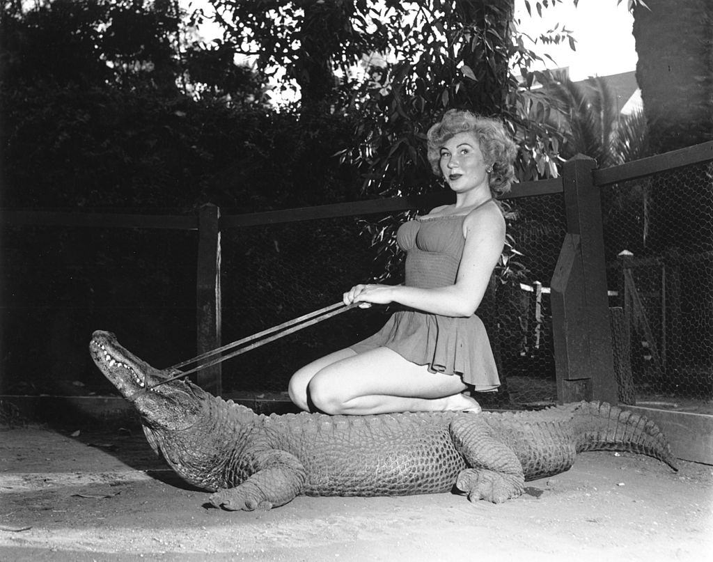 #15 A woman poses for a portrait while riding an alligator at The Los Angeles Alligator Farm.
