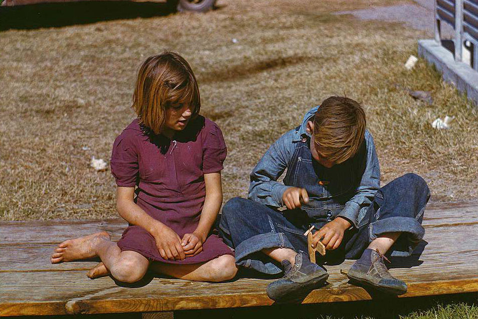 #65 Boy building a model airplane as girl watches, FSA camp, Robstown, Texas, 1950s