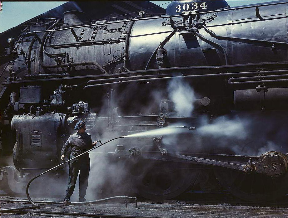 #88 Mrs. Viola Sievers, one of the wipers at the roundhouse giving a giant “H” class locomotive a bath of live steam, Clinton, Iowa, 1950s
