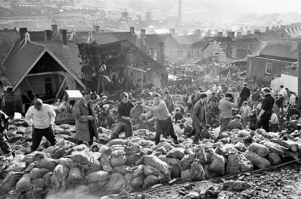 #116 Rescue workers bagging and moving some of the coal spoil following the catastrophic collapse of a colliery spoil tip in the Welsh village of Aberfan, near Merthyr Tydfil, on 21 October 1966.