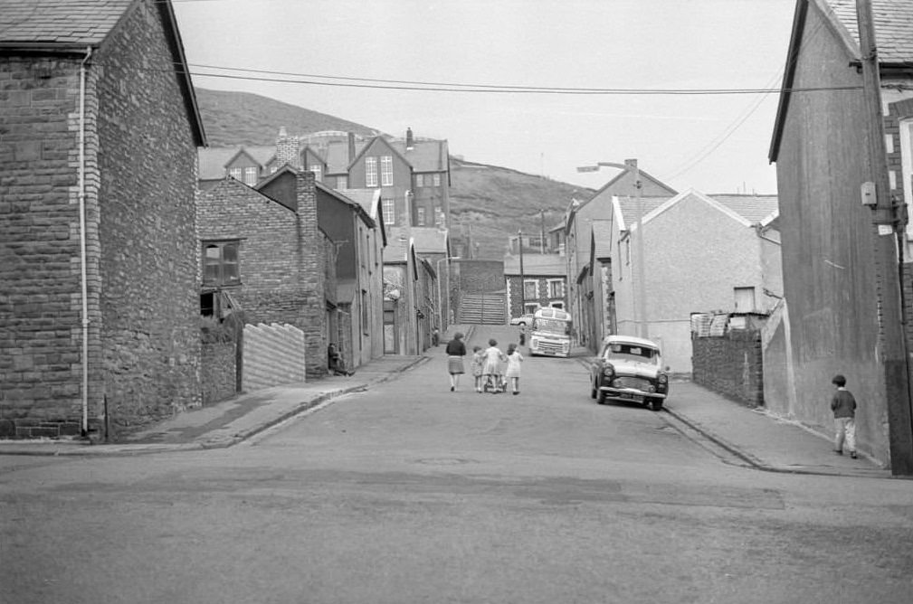 #45 A mother and her three children walk along a near empty street in the mining town of Tonypandy, Wales, United Kingdom, 1966.