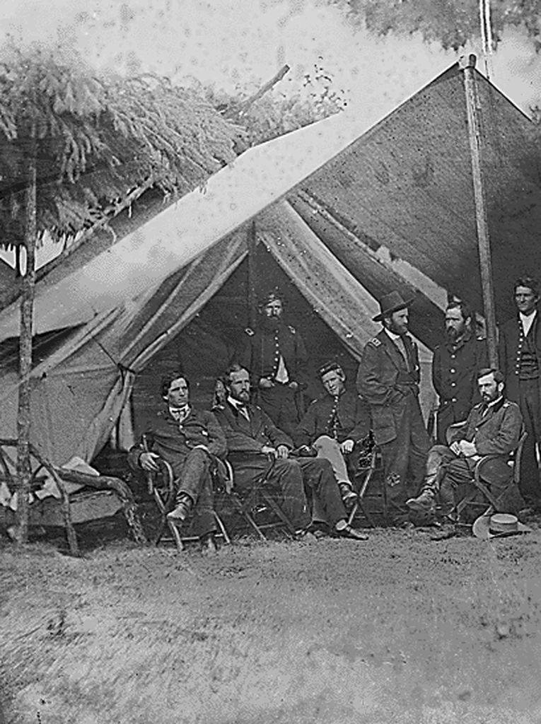 #39 Former US Lt. General Ulysses S. Grant (standing 5th from L) next to a tent with his fellow officers during the US Civil War, 1865.